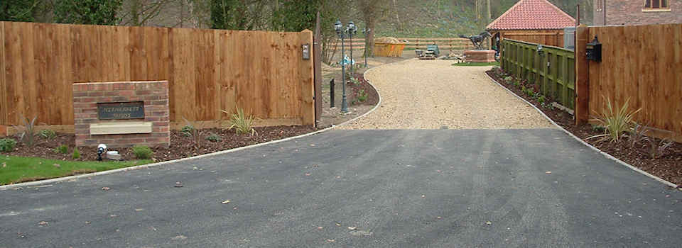 Asphalt drive entrance with kerbstone edging and shingle drive, fencing, turf, garden lighting and landscaping